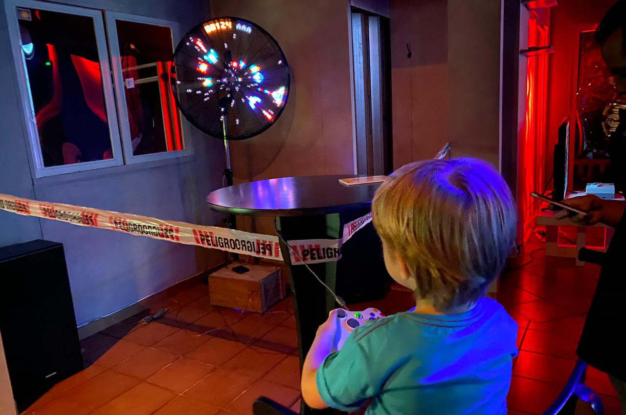 A player holding a joystick in front of Ventilastation’s glowing fan display